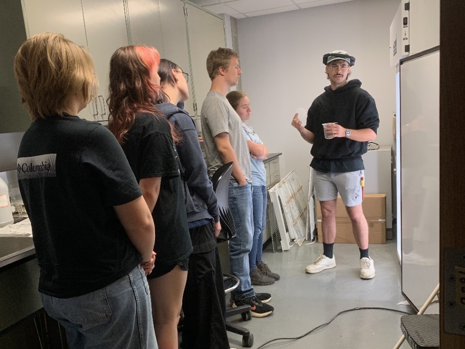 NKU Biological Sciences student teaching procedures for analyzing mosquito larvae and pupae in incubator.