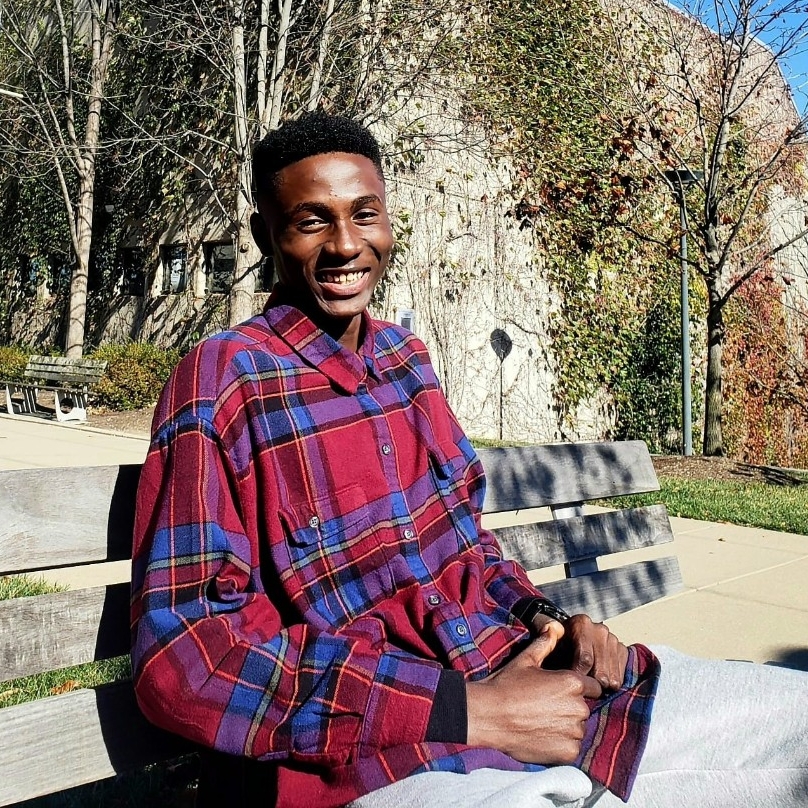 Joshua Osakwe sitting on a bench outside