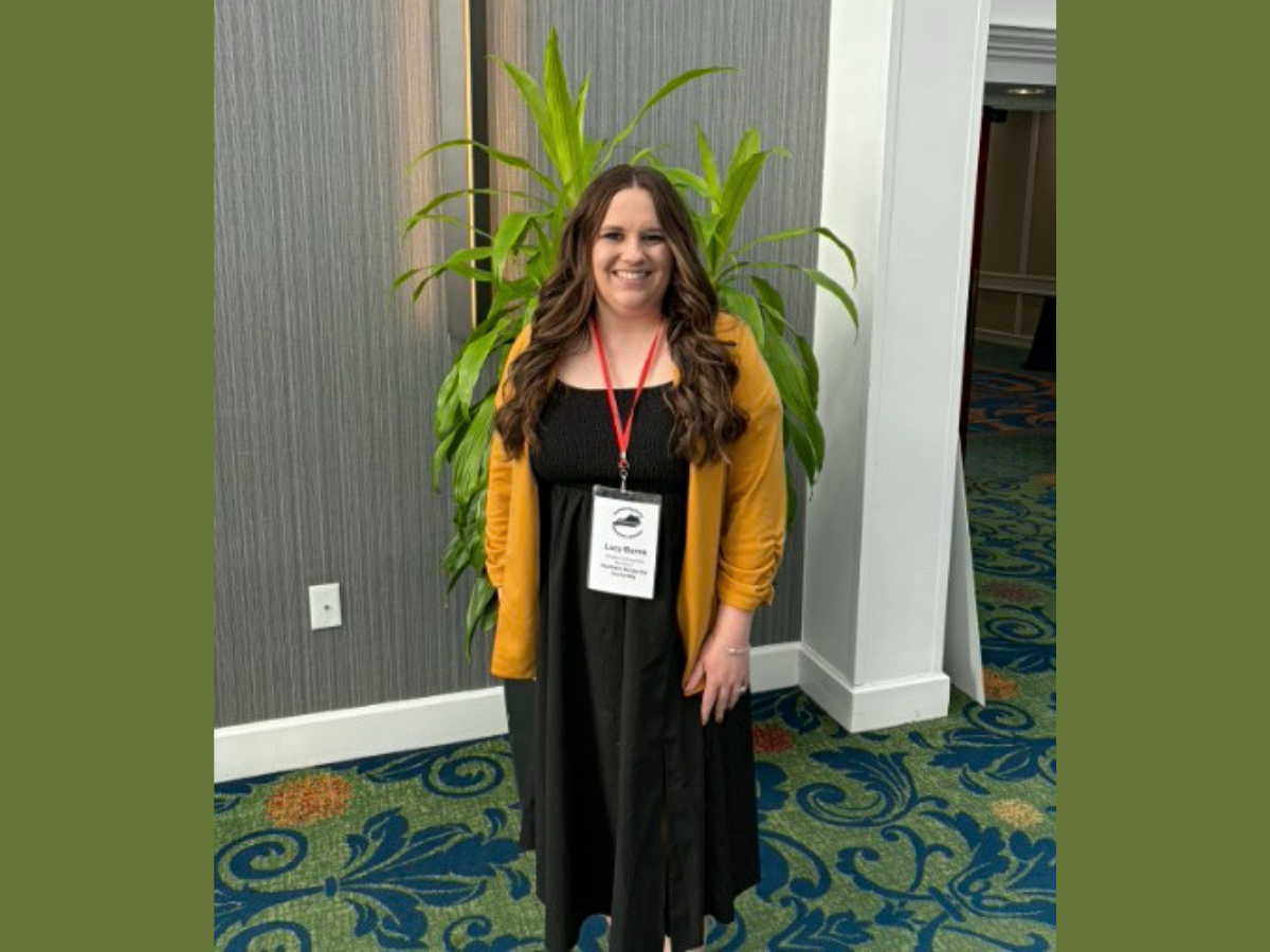 Lucy Burns standing in front of a plant at the conference