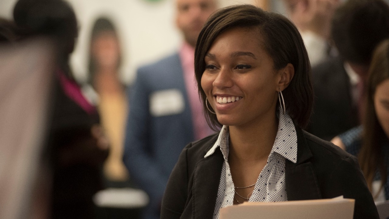 Woman smiling as she talks with someone at a career fair